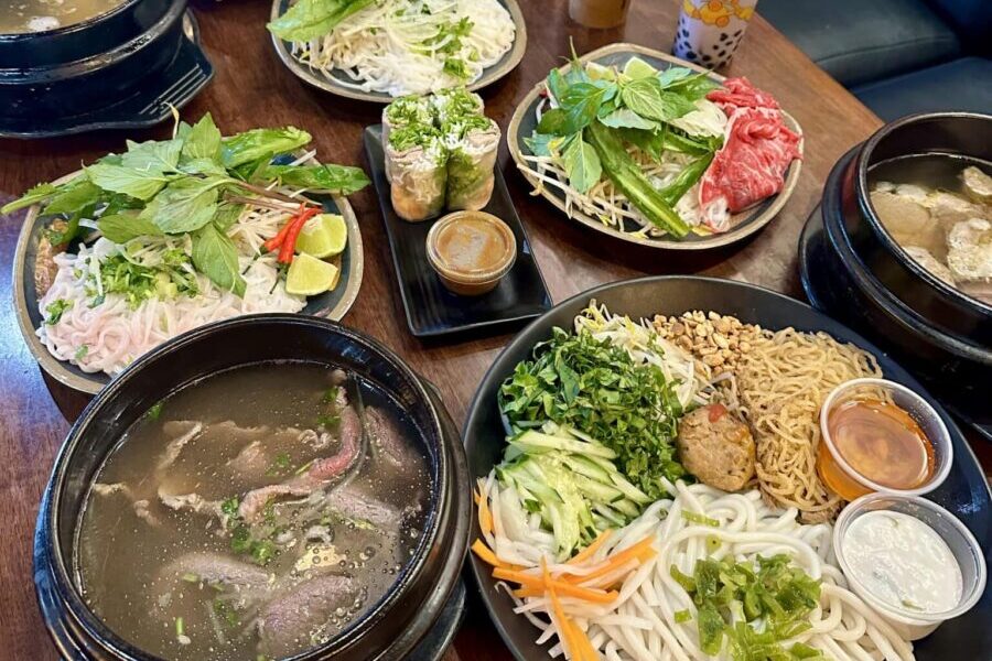 Pho and other Vietnamese dishes on a table with drinks