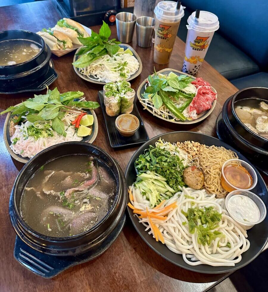 Pho and other Vietnamese dishes on a table with drinks