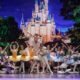 Ballet dancers on stage during a production of Cinderella. The dancers are posed in front of a lit backdrop of Cinderella's castle.