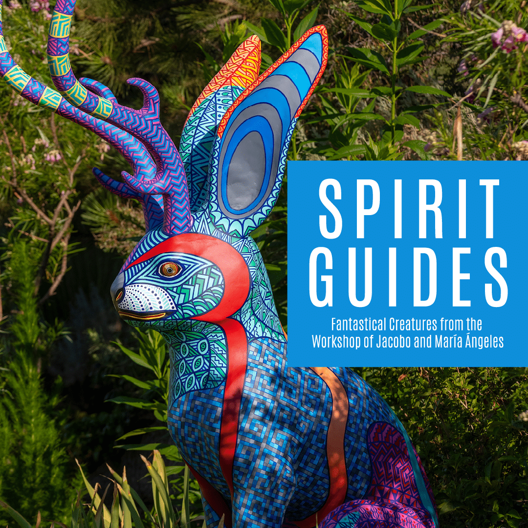 Fernbank Spirit Guides exhibit promotion with colorful wooden animal sculpture in a grassy area with lots of trees and bushes.