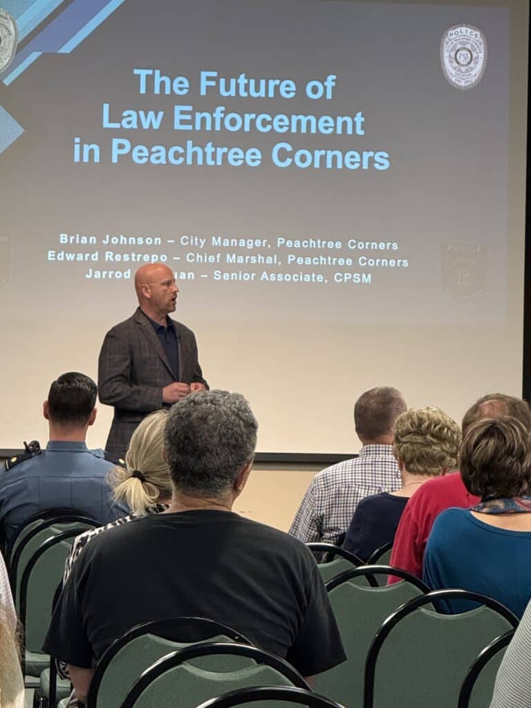 Brian Johnson speaking to the audience at a public city meeting on May 8, 2025
