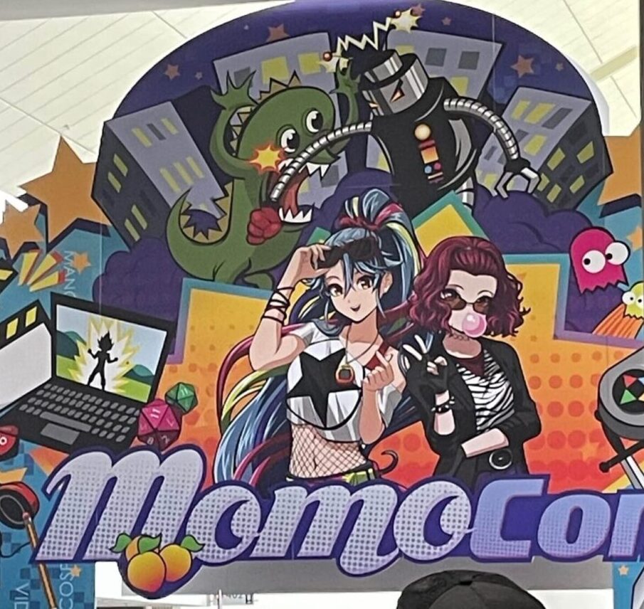MomoCon 2025 entrance with colorful anime-style illustration and logo