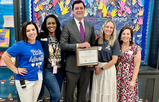 Four women and one man standing in front of a colorful wall at an elementary school for Exceptional Children's Week