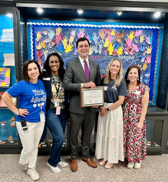 Four women and one man standing in front of a colorful wall at an elementary school for Exceptional Children's Week