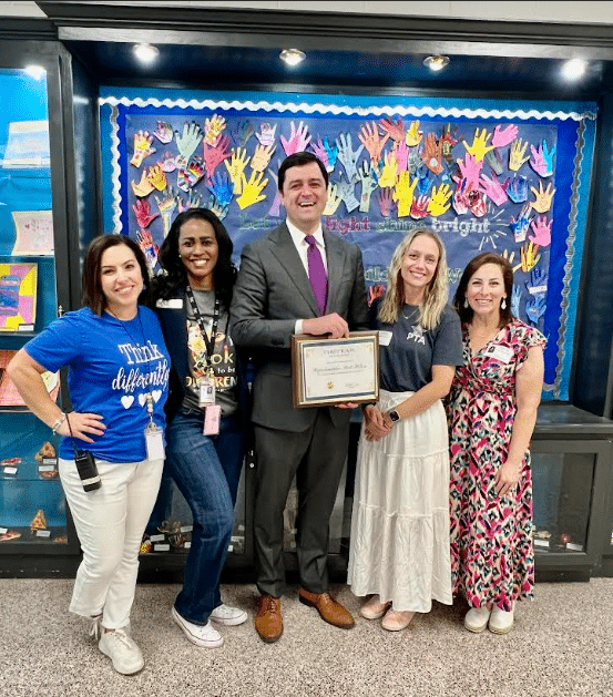 Four women and one man standing in front of a colorful wall at an elementary school for Exceptional Children's Week