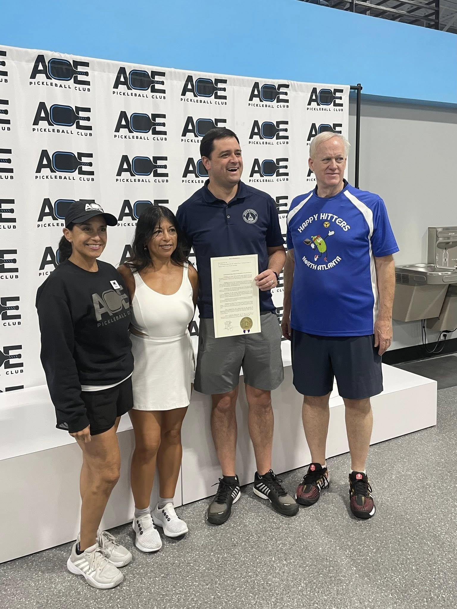 GA State Rep. Scott Hilton stands with two coaches and the manager of a Special Olympics of Georgia pickleball team, awarding House Resolution 700 commending them for their work.
