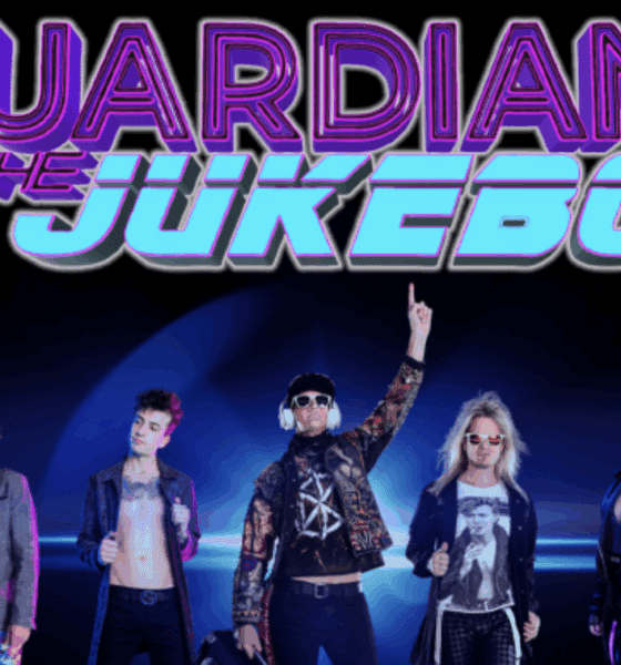 Guardians of the Jukebox 80s cover band in costume on stage with their 80s-style logo above them.
