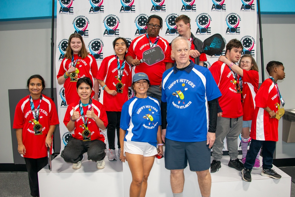 A Special Olympics pickleball team posing with their coaches and their medals