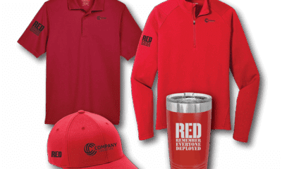 Two red shirts, a red cap and a red tumbler with RED Remember Everyone Deployed on it in white text, all against a white background