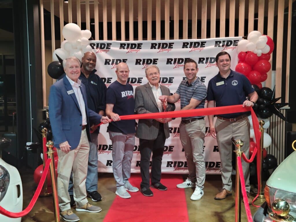 A group of men at an indoor ribbon cutting ceremony for Ride Lounge