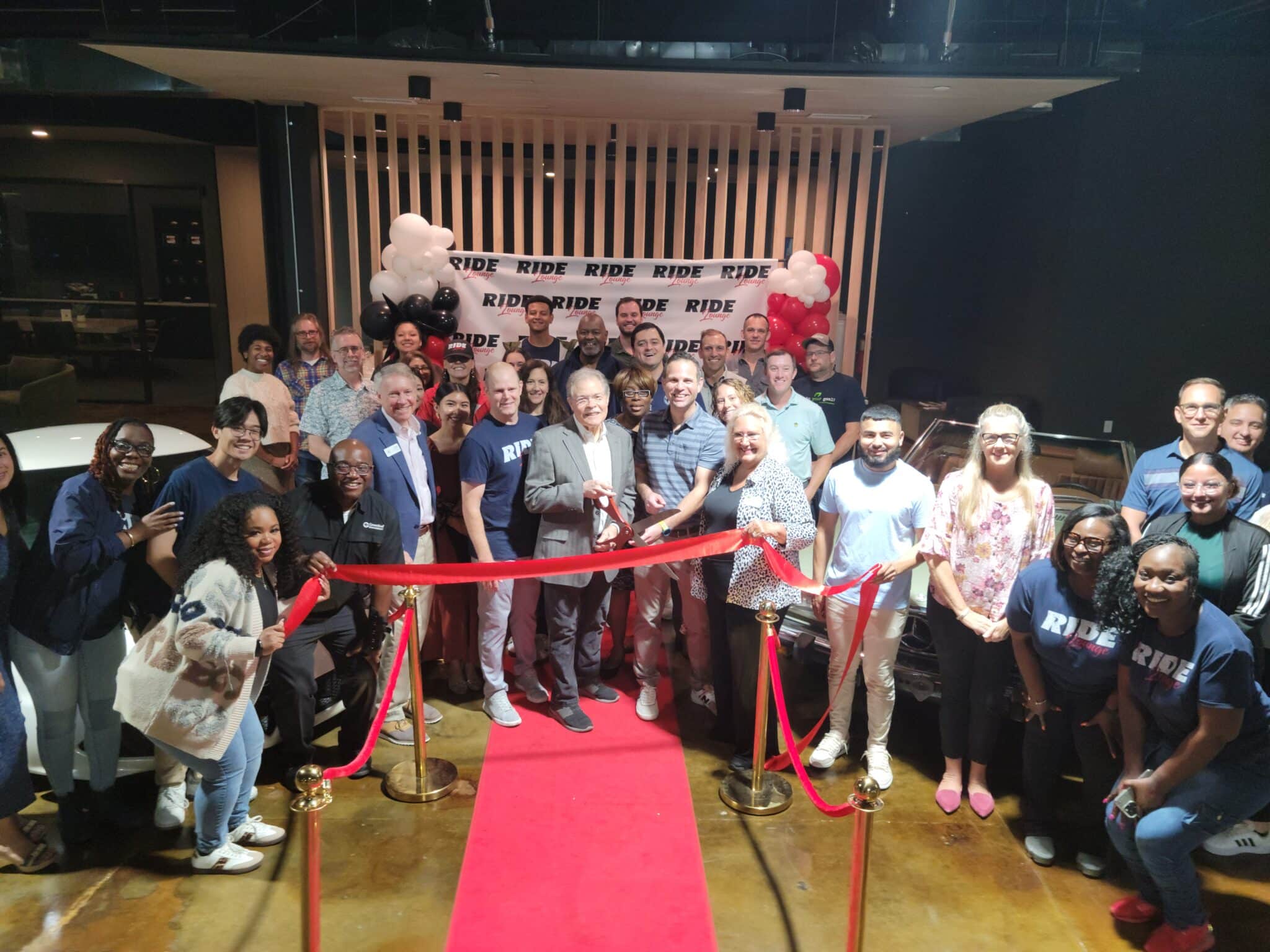 A group of people at an indoor ribbon cutting ceremony for Ride Lounge
