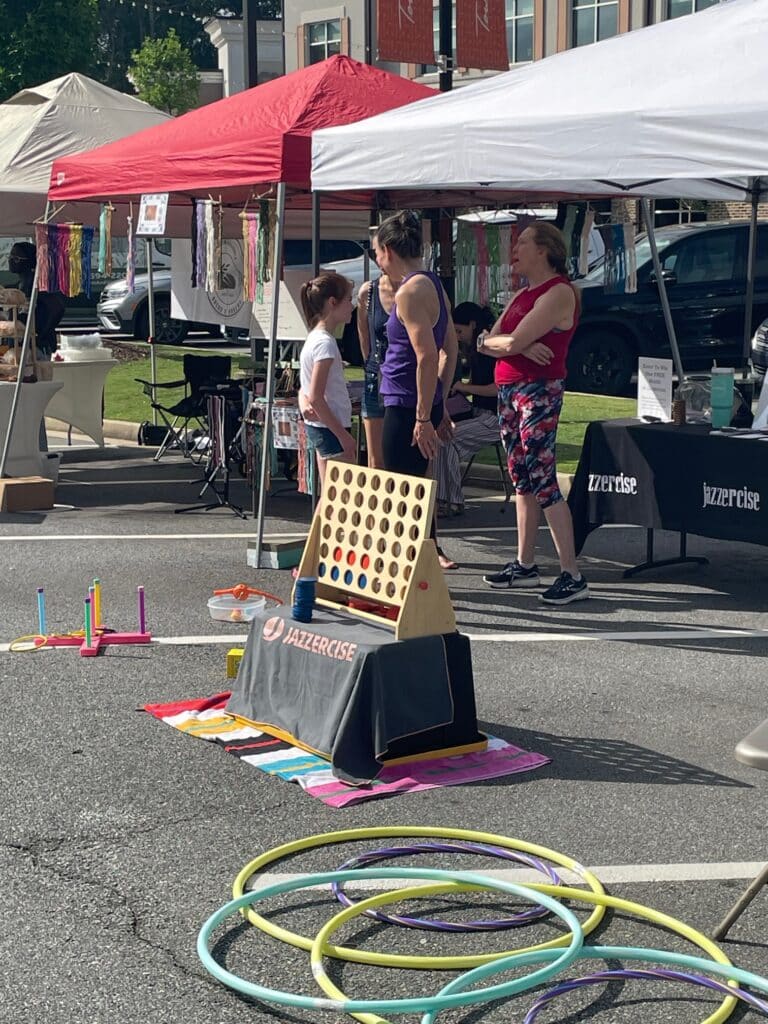 Outdoor kids games next to a tented booth at an outdoor farmers market.