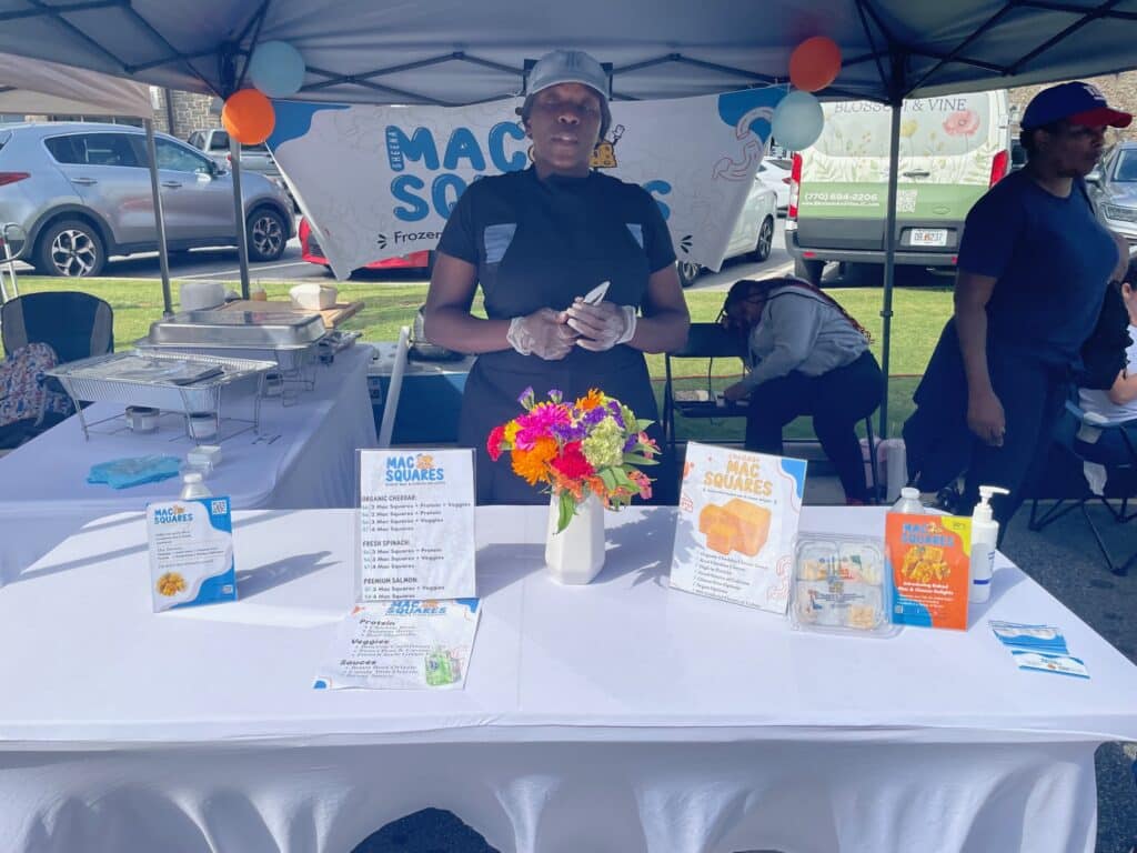 A booth selling mac 'n cheese squares at an outdoor farmers market.