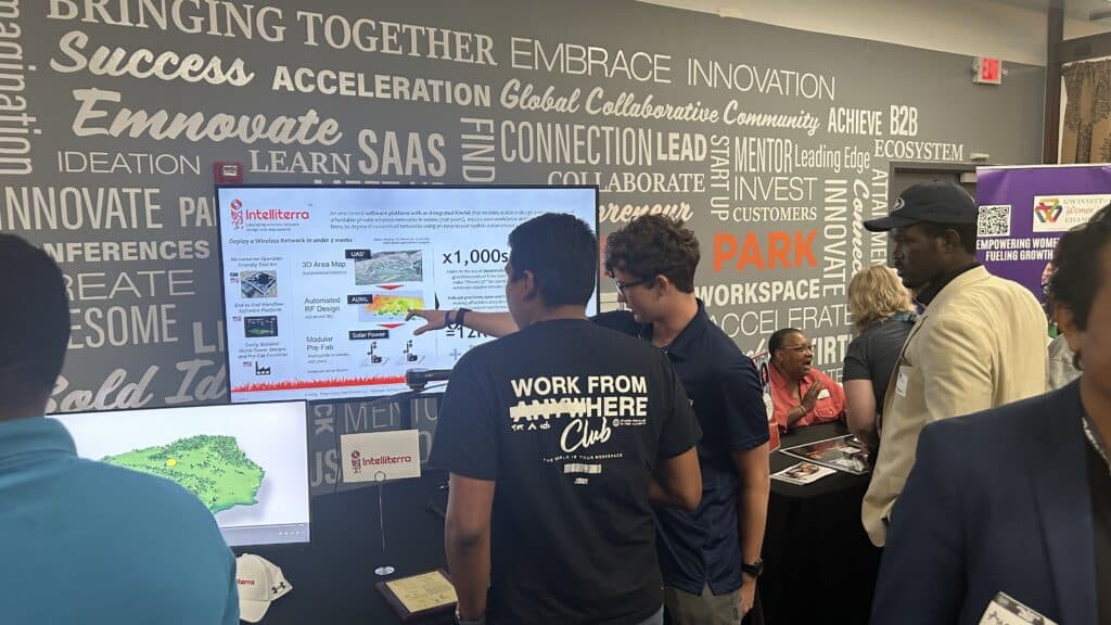 A group of people looking at a large computer screen at a tech conference