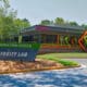 Exterior of the Curiosity Lab campus in Peachtree Corners. There's a building with T-Mobile signage, and entrance sign that reads "Innovation Center Curiosity Lab" and a small parking lot surrounded by grass and trees.